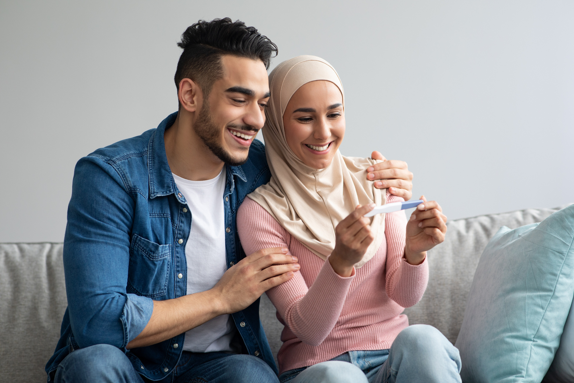 Happy pregnant muslim couple with pregnancy test at home