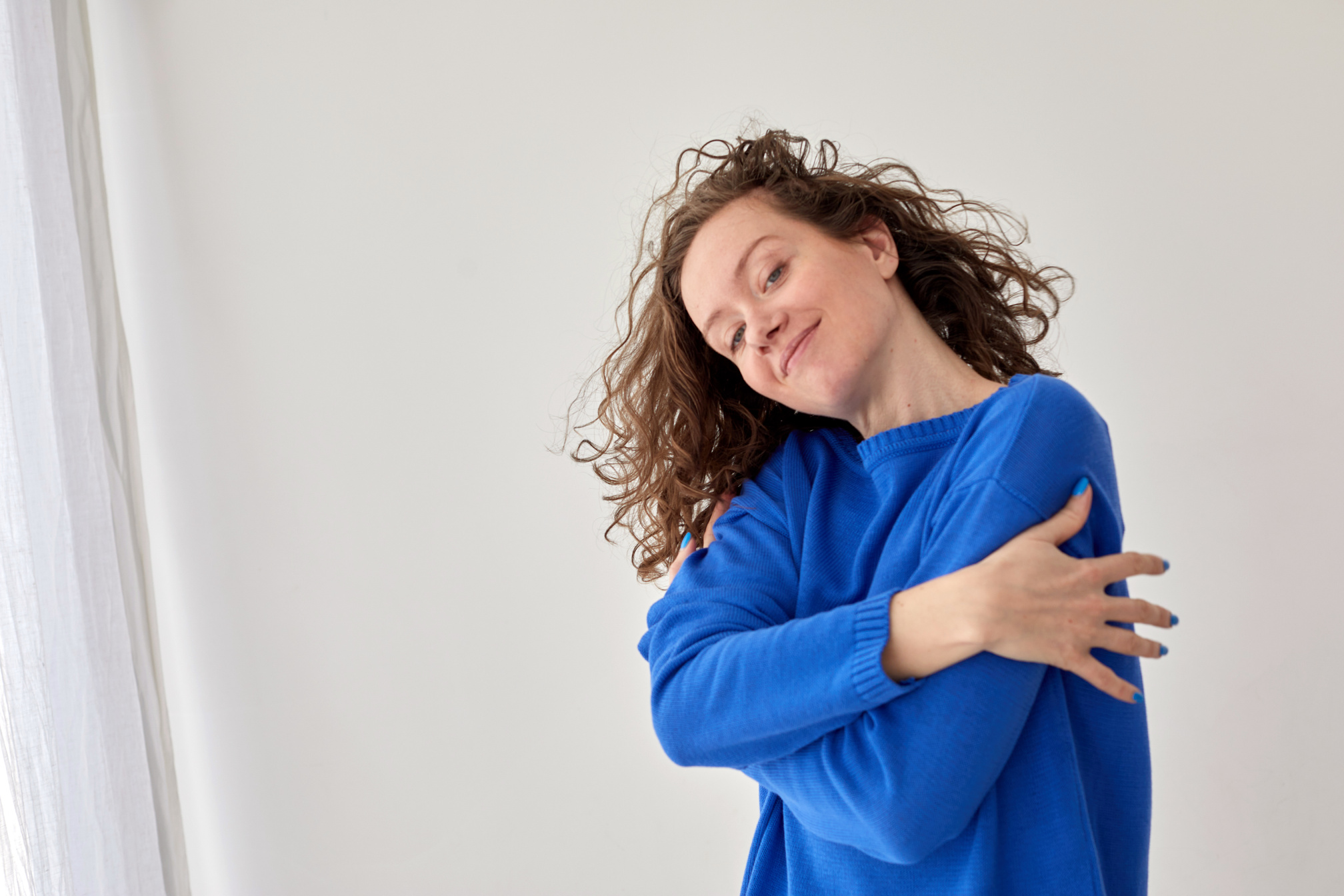 Self Hug of Happy Confident Young Woman against White Wall Background