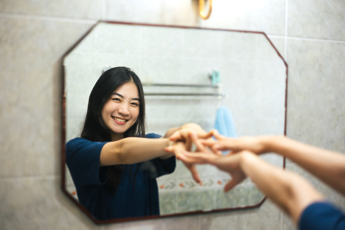 Young adult smile asian woman practice self talk conversation with mirror.