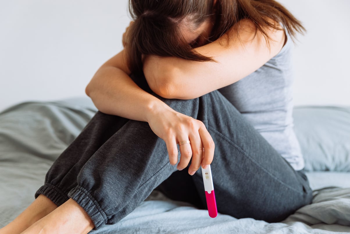 Sad Woman on Bed with Negative Pregnancy Test