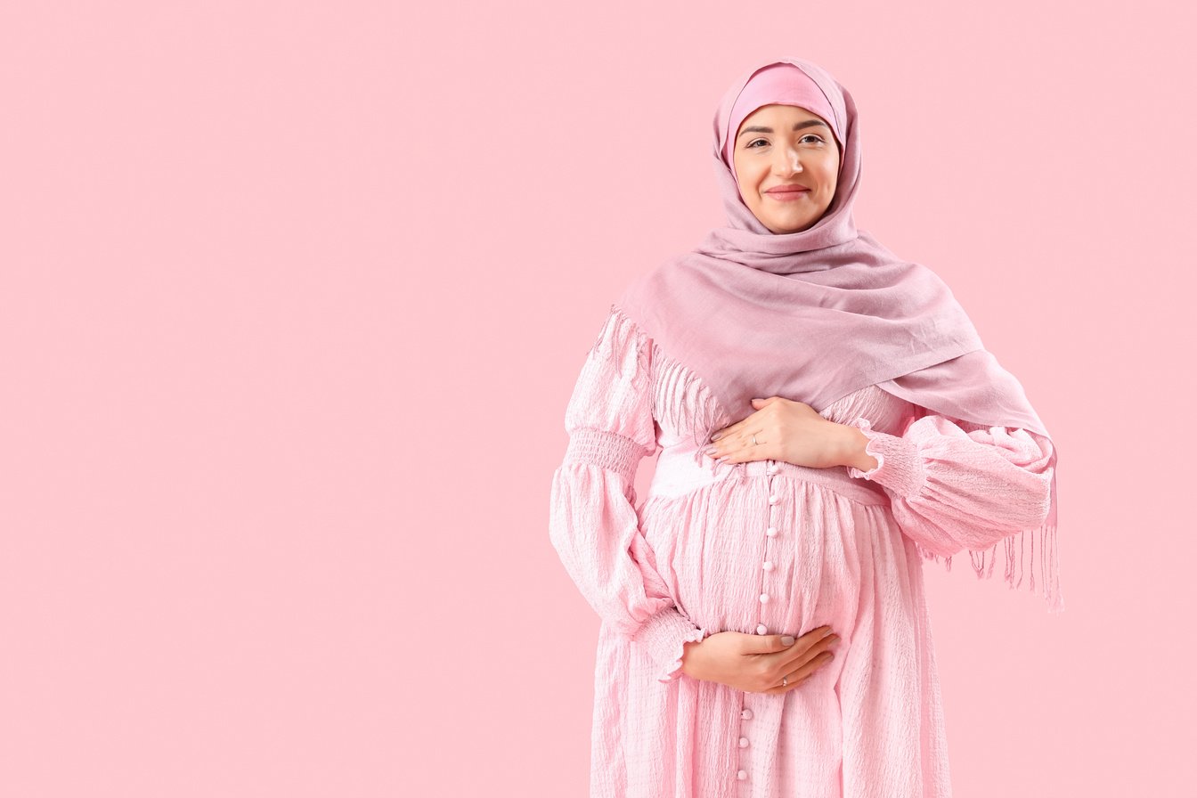 Young Pregnant Muslim Woman on Pink Background