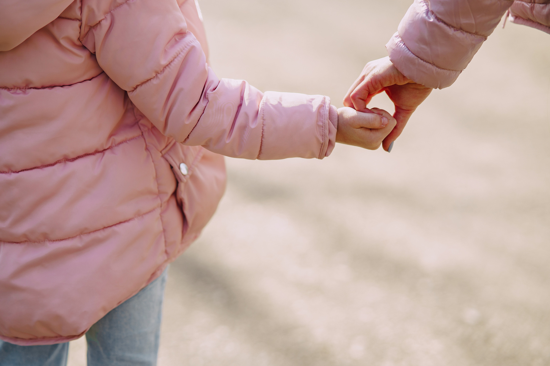 Crop daughter standing hand in hand with mother in city